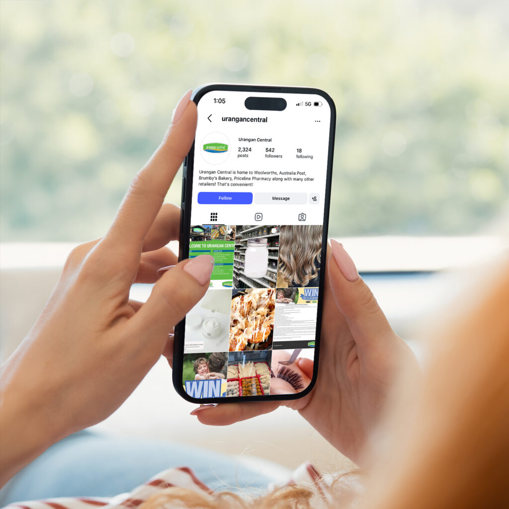 Hands holding a phone showing the Urangan Central Instagram page